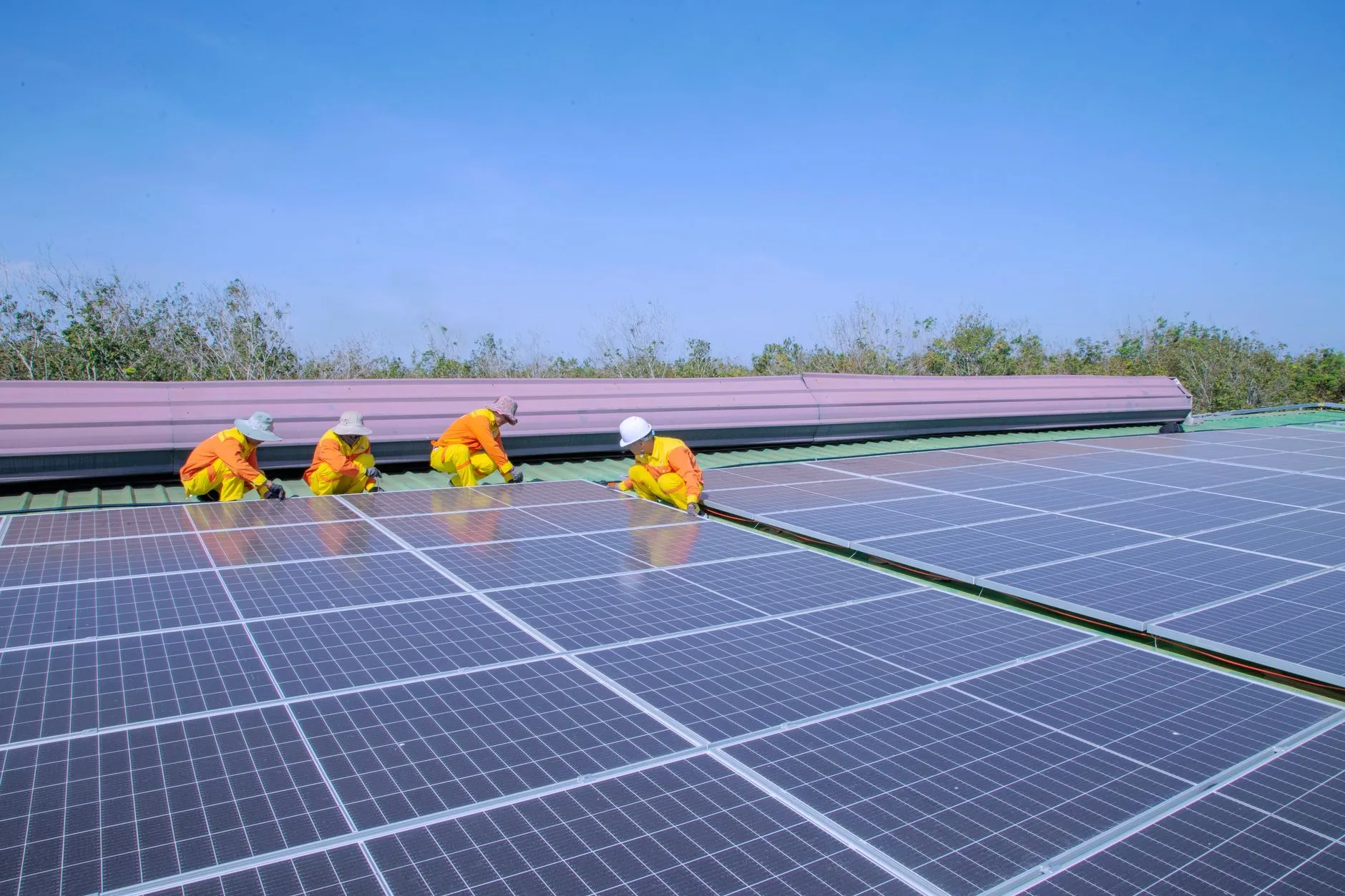 Montageteam installiert Solarmodule auf einem Dach unter blauem Himmel