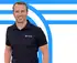 Lächelnder Mann im schwarzen Poloshirt mit "TICON"-Logo vor blau-weißem Hintergrund mit stilisierten Linien.